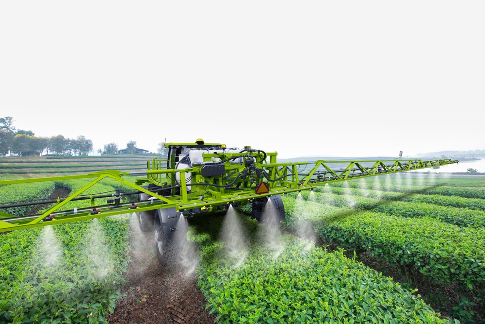 Agriculture tractor spraying fertilizer on green tea fields, Technology smart farm concept.